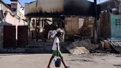 Muškarac nosi svoje stvari dok bježi kući nakon nasilja naoružanih bandi