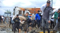 Palestinci nose vreće brašna koje su dobili iz kamiona humanitarne pomoći